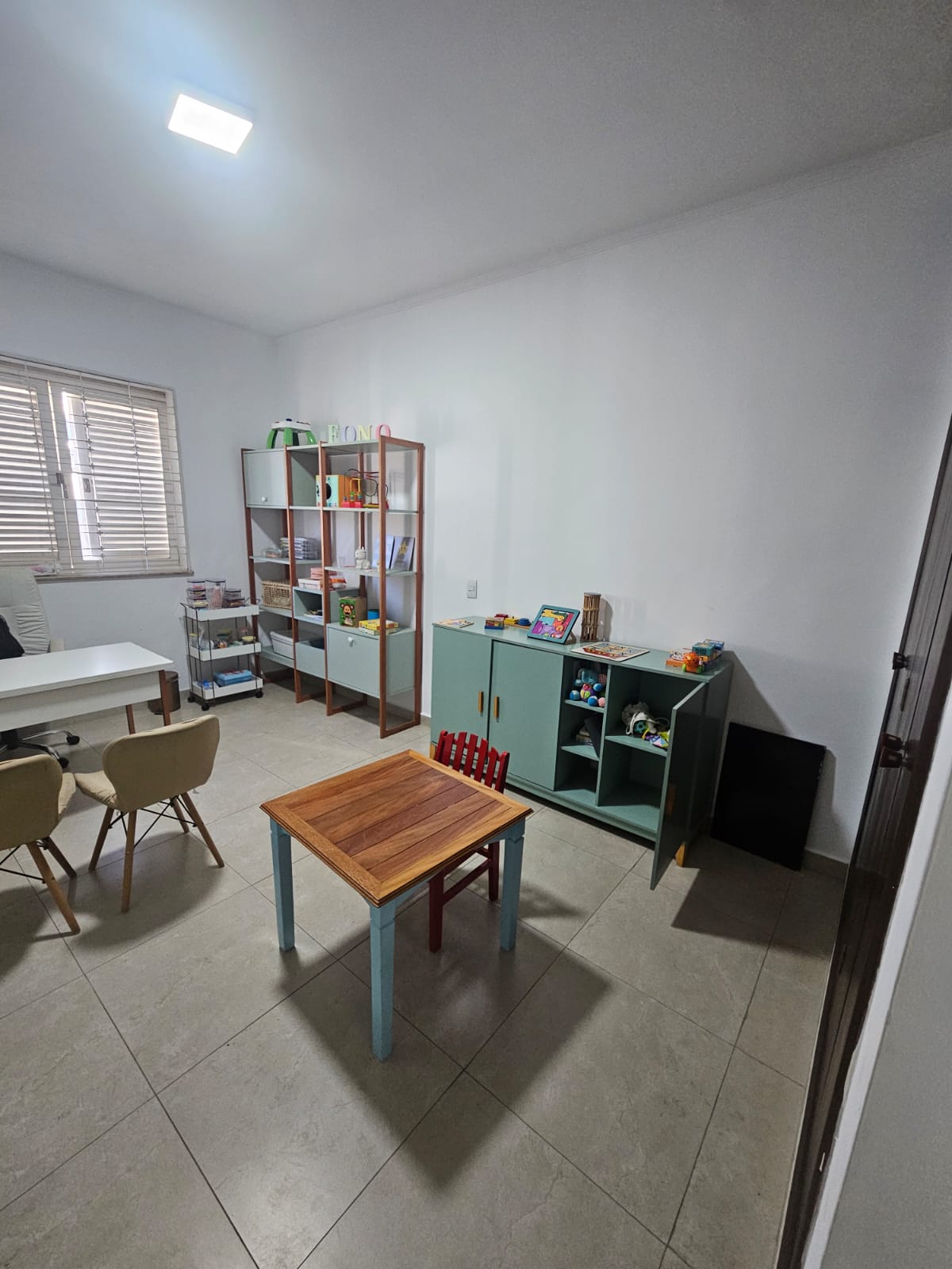 Sala de terapia infantil com mesa e materiais lúdicos